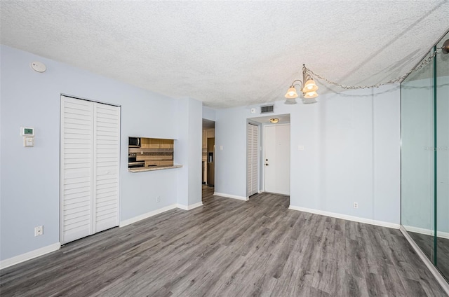 unfurnished living room with a textured ceiling, hardwood / wood-style flooring, and an inviting chandelier