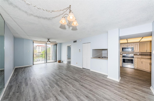 unfurnished living room featuring wood-type flooring, ceiling fan with notable chandelier, and a textured ceiling