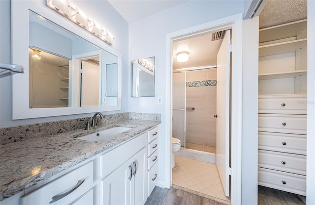 bathroom with toilet, vanity, an enclosed shower, and hardwood / wood-style flooring