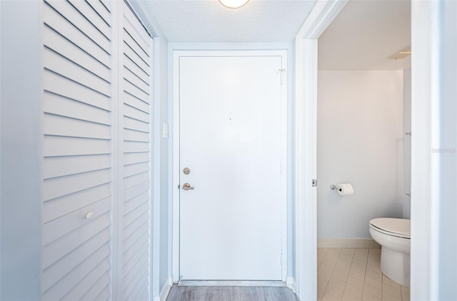 interior space with tile patterned flooring, a textured ceiling, and toilet