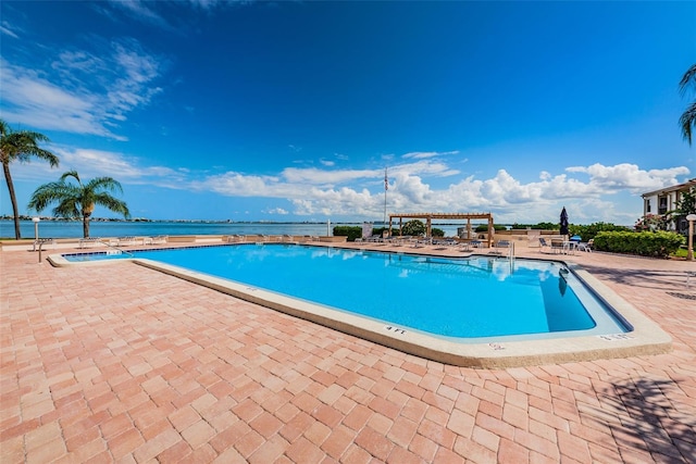 view of pool featuring a water view and a patio area