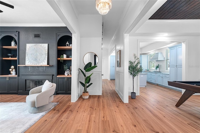 entryway with ornamental molding and light hardwood / wood-style flooring