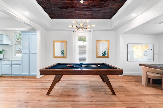 playroom with ornamental molding, an inviting chandelier, pool table, a tray ceiling, and light hardwood / wood-style flooring