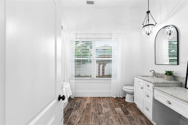 bathroom with wood-type flooring, a chandelier, toilet, and vanity