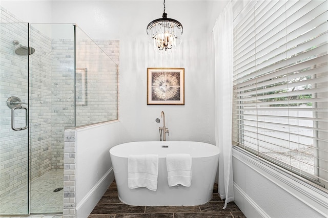 bathroom featuring a stall shower, a soaking tub, baseboards, and a notable chandelier