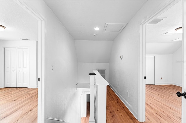 hall featuring lofted ceiling, attic access, an upstairs landing, and wood finished floors