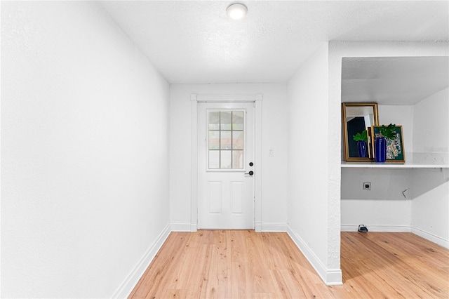 doorway to outside with light wood finished floors and baseboards