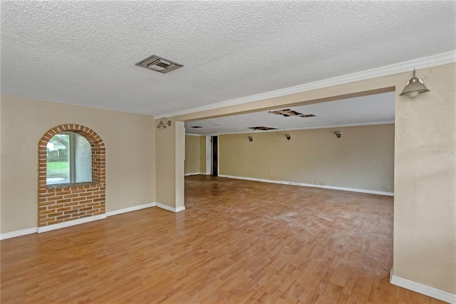 empty room with crown molding, a textured ceiling, and hardwood / wood-style flooring