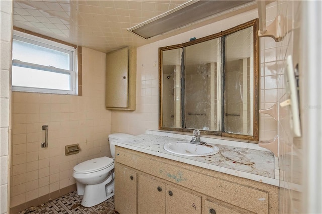 bathroom featuring tile patterned flooring, vanity, toilet, and tile walls