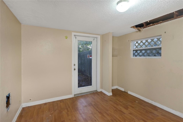 unfurnished room with hardwood / wood-style floors and a textured ceiling