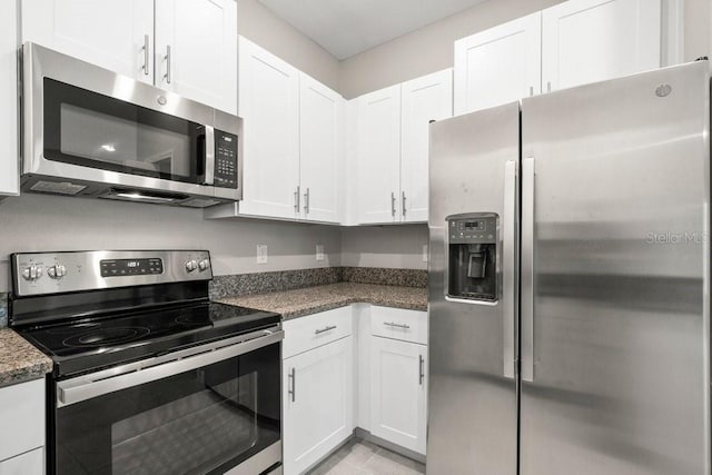 kitchen with white cabinets, appliances with stainless steel finishes, and dark stone counters