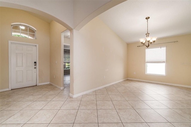 tiled entryway with a chandelier and vaulted ceiling