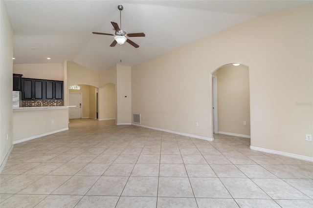 unfurnished living room with ceiling fan, light tile patterned floors, and vaulted ceiling