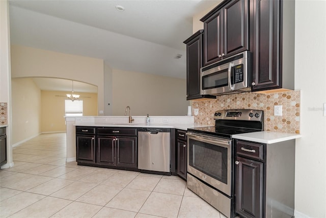 kitchen featuring backsplash, an inviting chandelier, sink, light tile patterned flooring, and stainless steel appliances