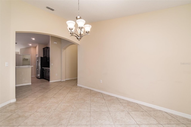 empty room with light tile patterned floors and a chandelier