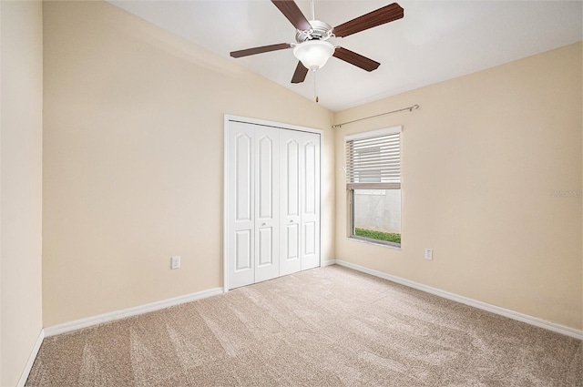 unfurnished bedroom featuring carpet flooring, a closet, lofted ceiling, and ceiling fan