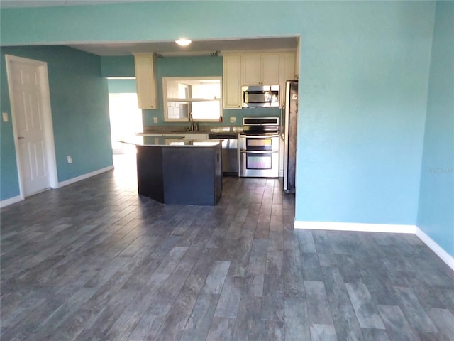 kitchen featuring stainless steel appliances, dark hardwood / wood-style floors, sink, white cabinets, and a center island