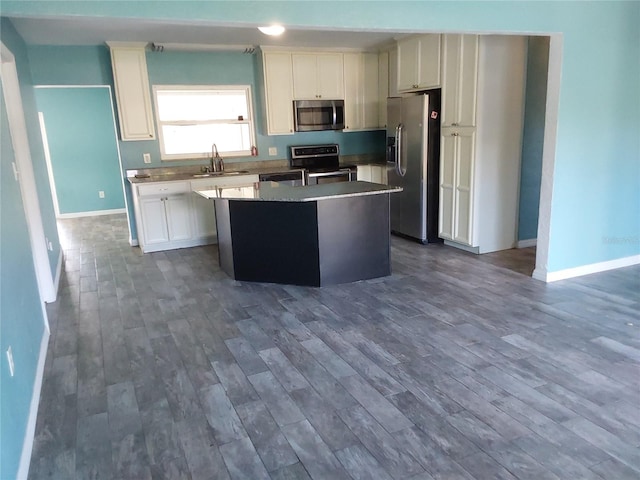 kitchen with dark hardwood / wood-style flooring, a center island, sink, white cabinetry, and appliances with stainless steel finishes