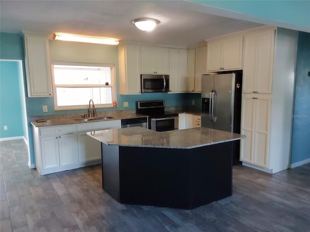 kitchen with white cabinetry, stainless steel appliances, sink, and a center island