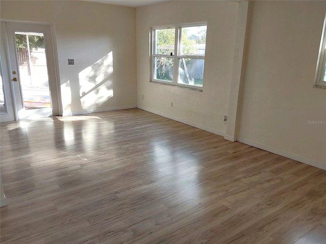 empty room with light hardwood / wood-style flooring and plenty of natural light