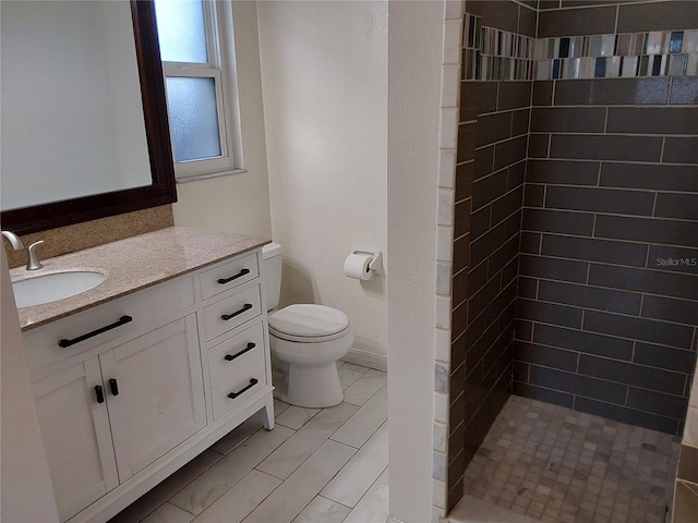 bathroom featuring vanity, toilet, and tiled shower