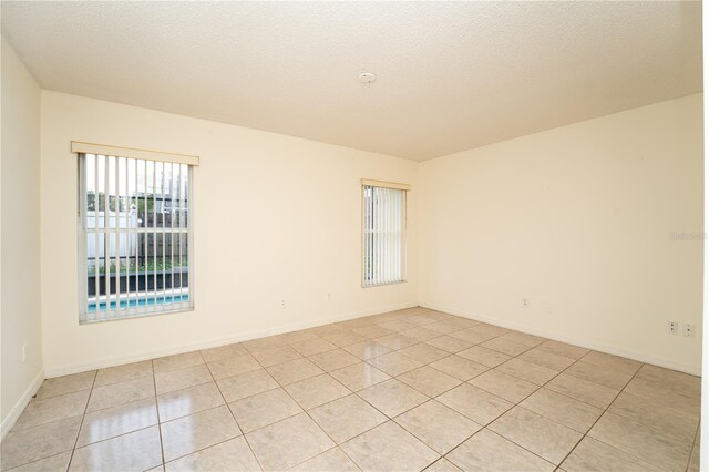 tiled spare room with a textured ceiling