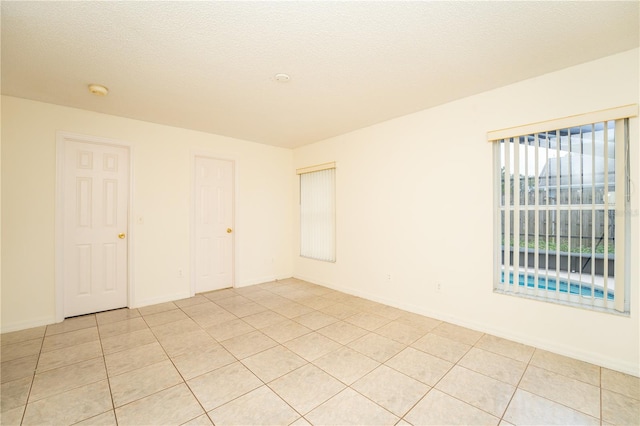 spare room featuring a textured ceiling and light tile patterned floors