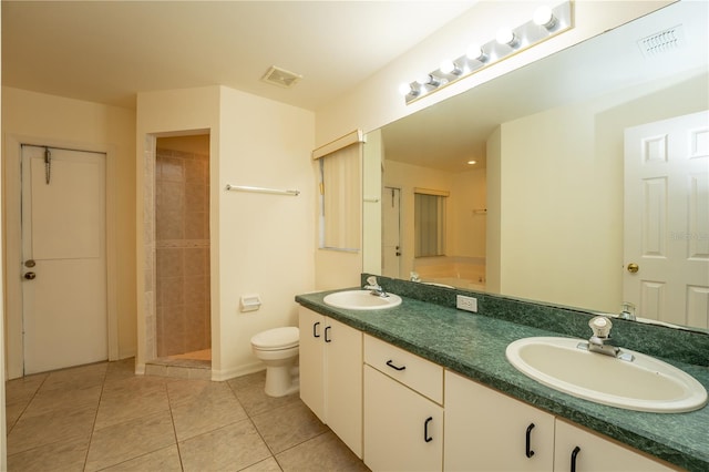 bathroom featuring tiled shower, vanity, tile patterned floors, and toilet