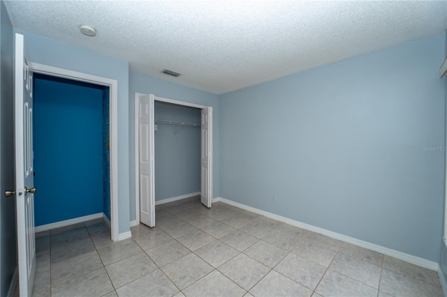 unfurnished bedroom featuring light tile patterned floors, a textured ceiling, and a closet