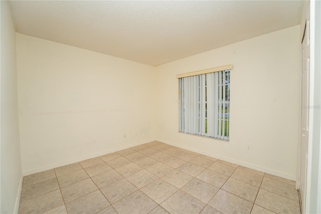 unfurnished room with a textured ceiling and light tile patterned floors