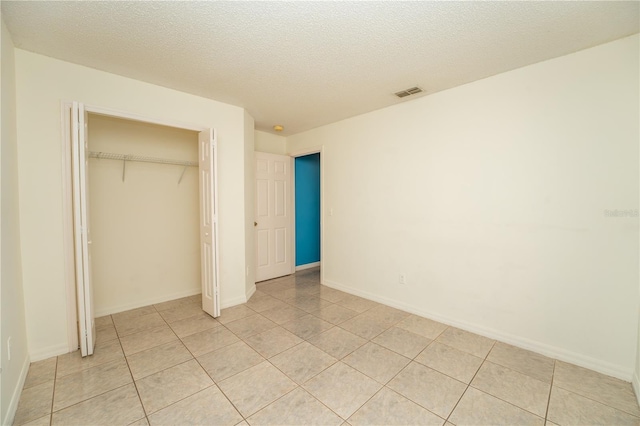 unfurnished bedroom featuring light tile patterned floors, a textured ceiling, and a closet