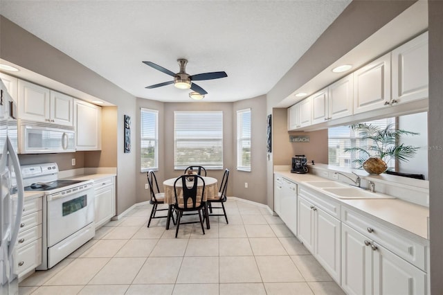 kitchen with white appliances, white cabinetry, and a healthy amount of sunlight