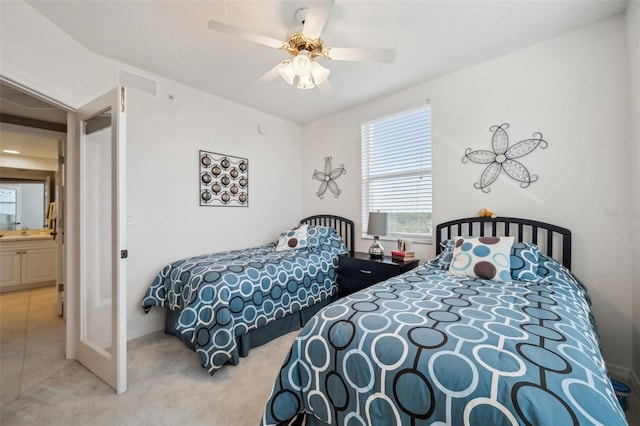 bedroom featuring connected bathroom, sink, light carpet, and ceiling fan