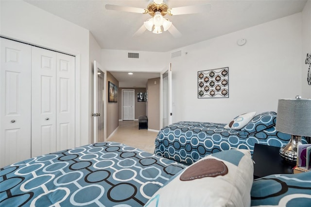 bedroom with ceiling fan, light carpet, and a closet