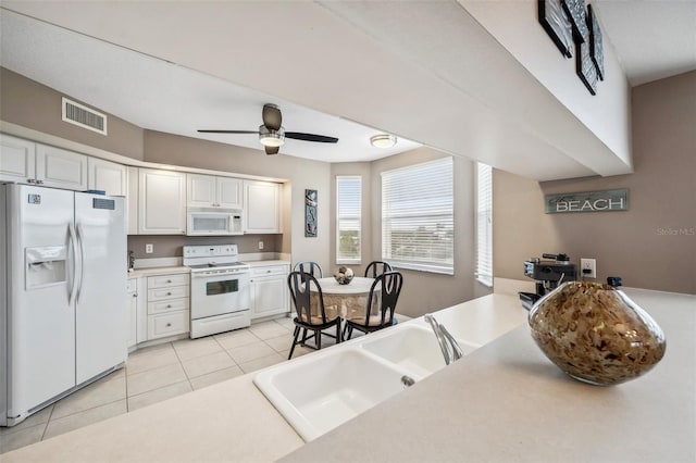 kitchen with light tile patterned floors, sink, ceiling fan, white cabinetry, and white appliances