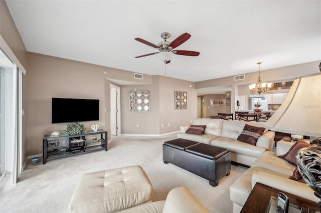 carpeted living room featuring ceiling fan with notable chandelier