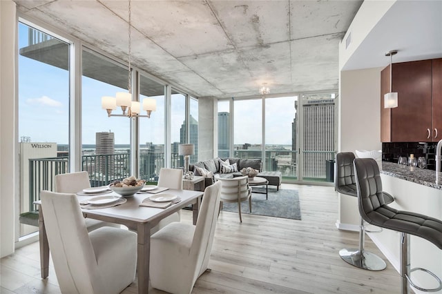 dining room featuring an inviting chandelier, floor to ceiling windows, and light wood-type flooring