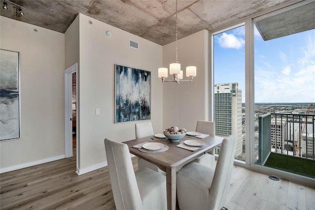 dining space with an inviting chandelier, light hardwood / wood-style flooring, and expansive windows