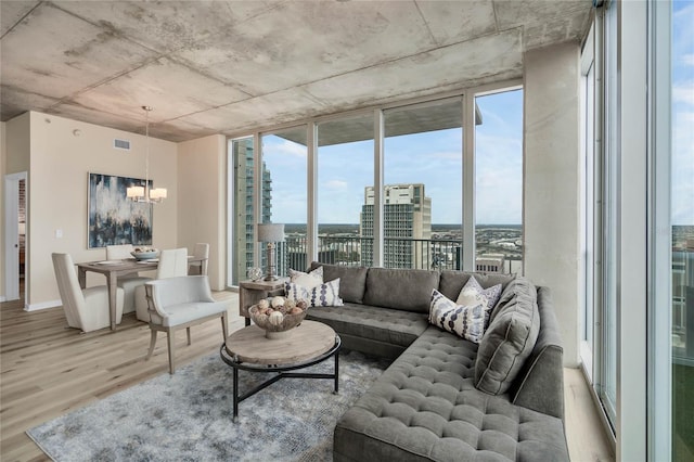 living room featuring an inviting chandelier, a wall of windows, and light hardwood / wood-style flooring