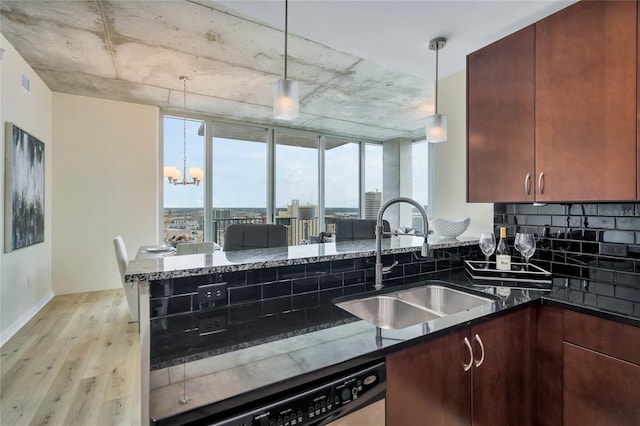 kitchen featuring sink, decorative light fixtures, stainless steel dishwasher, and dark stone counters