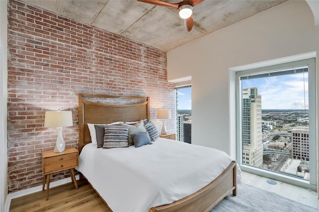 bedroom with ceiling fan, brick wall, and light hardwood / wood-style floors