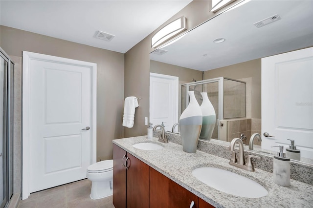 bathroom with tile patterned flooring, vanity, a shower with door, and toilet