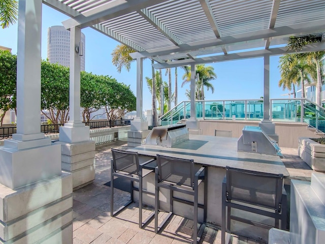 view of patio featuring exterior bar, a pergola, grilling area, and an outdoor kitchen