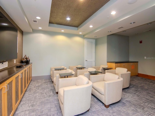 home theater with a raised ceiling and dark colored carpet