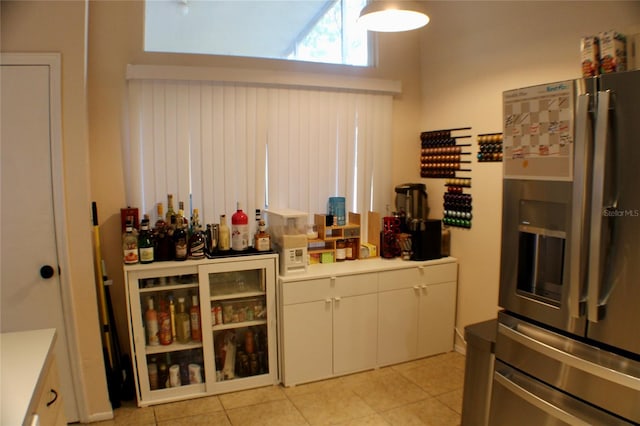 kitchen featuring stainless steel fridge with ice dispenser, light tile patterned floors, and white cabinets