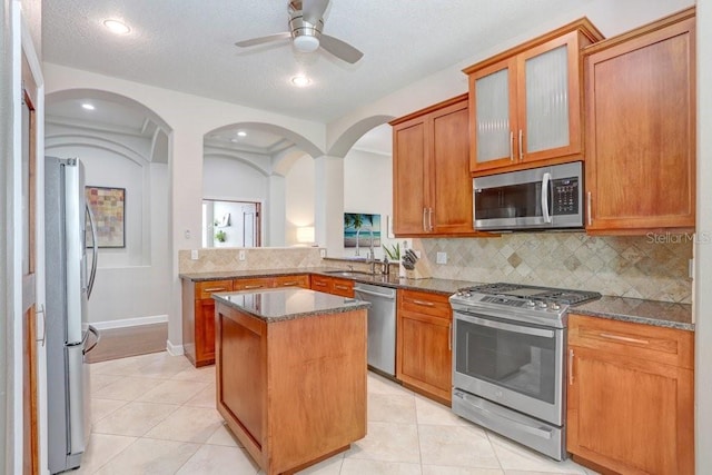 kitchen featuring stone counters, a kitchen island, light tile patterned floors, and appliances with stainless steel finishes