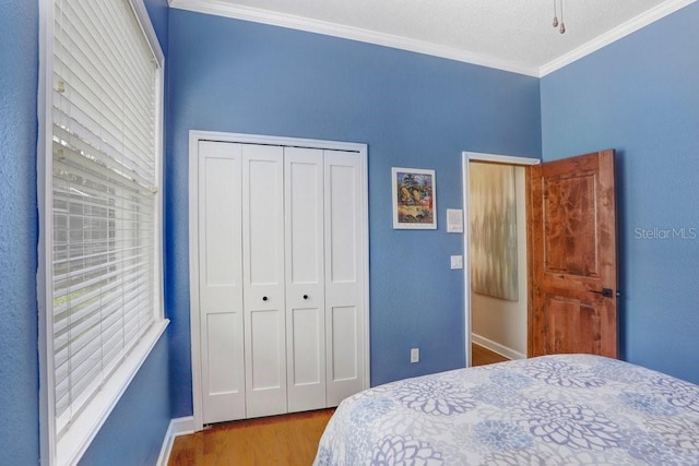 bedroom with a closet, crown molding, and light hardwood / wood-style flooring