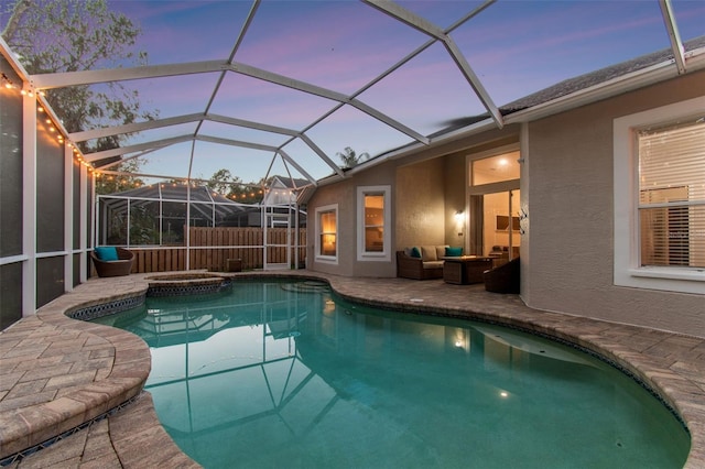 pool at dusk with an in ground hot tub, an outdoor living space, glass enclosure, and a patio area