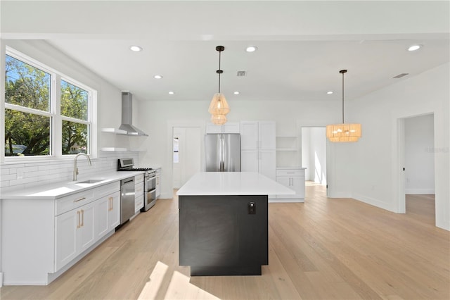 kitchen featuring hanging light fixtures, appliances with stainless steel finishes, wall chimney exhaust hood, and a kitchen island