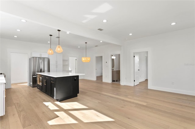 kitchen featuring a kitchen island, decorative light fixtures, stainless steel refrigerator, light hardwood / wood-style floors, and white cabinets